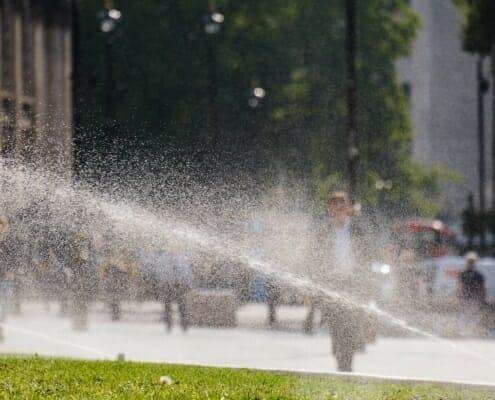 A commercial irrigation system distributing water on the property as people walk around.