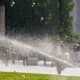 A commercial irrigation system distributing water on the property as people walk around.