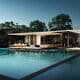 Luxury custom pool and patio outside of a modern white house with a blue sky